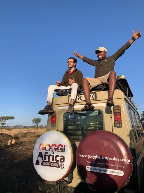 Goggi guide and guest celebrating on the roof of the safari vehicle