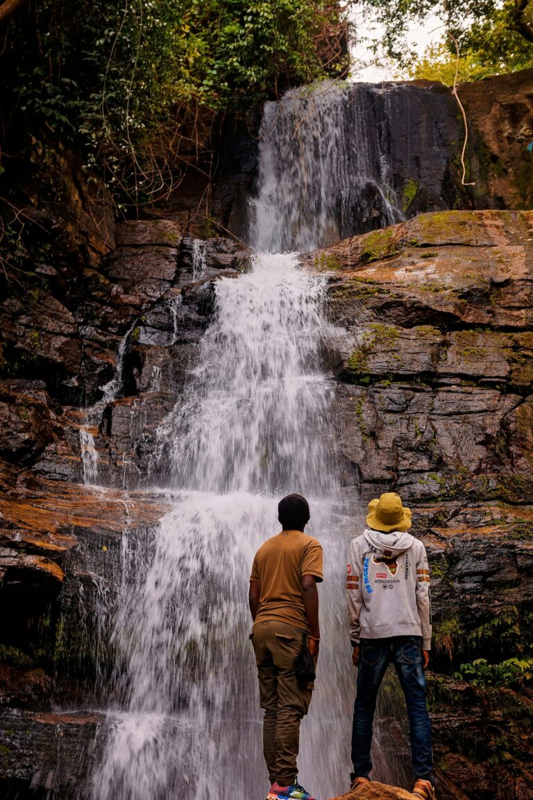 Two visitors in front of a waterfall